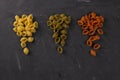 Top view of dry conchiglie pasta on black board background. Three triangular slides with pasta conchiglie spread out in colors,