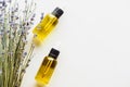 Top view of dry lavender twigs with flowers and bottles with natural oil on white background with copy space.