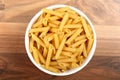 Top view of dry penne rigate in white ceramic bowl