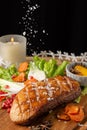 Top view of duck breast with falling salt, lettuce, chives and peaches, on table with vel and Christmas decoration, black backgrou