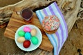 Top view of Easter colored eggs, Easter cake and a mug of black tea lying on white plates Royalty Free Stock Photo