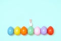 Top view of an Easter composition of painted eggs in bright juicy colors on a blue background with a little rabbit. Holiday concep