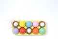 Top view of an Easter composition of painted eggs in bright juicy colors with a glossy texture that lie in a container with hay ne