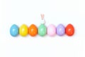 Top view of an Easter composition of painted eggs in bright juicy colors on a white background with a little rabbit. Holiday conce