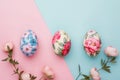 top view of Easter eggs with flower pattern and spring flowers on blue and pink background. Royalty Free Stock Photo