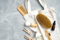 Top view eco-friendly bath accessories with canvas bag on stone table. Flat lay wooden hair comb, brush, essential oil, loofah