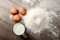 Top view of the egg, flour, a glass of fresh milk, cooking dough on the background of a wooden table. Flat lay Royalty Free Stock Photo