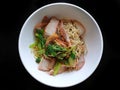 Top view of egg noodle with bbq pork, shrimp wonton topped with sliced scallion in white bowl isolated on black background Royalty Free Stock Photo