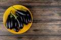 top view of eggplants in plate on left side and wooden background with copy space Royalty Free Stock Photo