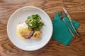 Top view of eggs benedict with toast and smoked ham, served with salad and mashed potato on white warm plate with green napkin. Royalty Free Stock Photo