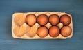 Top view of eggs in a box on a blue wooden background Royalty Free Stock Photo