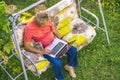 Top view of eldery man sitting and relaxing on summer holiday rasort using laptop on grass on couch Royalty Free Stock Photo