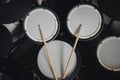 Top view of a electronic drum kit with cymbals and drums and a pair of wooden drumsticks, on a black background