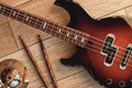 Top view of electronic guitar with wooden sticks and golden cymbal lying on wooden background. Musical instruments.