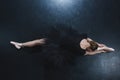 top view of elegant ballerina in pointe shoes and black tutu sitting