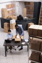 Top view of employees looking at cargo stock on laptop computer while putting client order in cardboard box Royalty Free Stock Photo