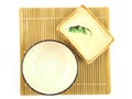 Top view, empty beige ceramic bowl and small plate on bamboo mat isolated on a white background. Royalty Free Stock Photo