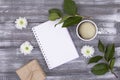 Top view of empty diary for ideas, plans, cup of coffee, gift wrapped in kraft paper, green branch and white Royalty Free Stock Photo