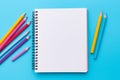 Top view of empty notebook with colorful crayon pencils on pastel blue background