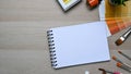 Empty notebook surrounded by color swatches, paintbrushes and copy space on wooden background. Royalty Free Stock Photo