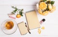 top view of empty open notebook with pen, flowers English rose, cosmetics and cup of tea on table top