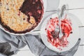 Top view of an empty plate with forks on it after pie. part of a crumble berry pie has been eaten. wooden table