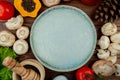 top view of an empty plate and fresh mushrooms with black peppercorns fresh tomatoes wooden mortar with dried herbs salt and cones Royalty Free Stock Photo