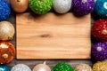 Top view of empty plate surrounded with colorful baubles on wooden background. New Year decorations. Christmas Eve concept Royalty Free Stock Photo