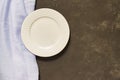 Top view of empty served plate, blue textile on black concrete background. Copy space