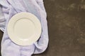 Top view of empty served plate, gray textile on black concrete background. Copy space