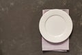 Top view of empty served plate, gray textile napkin on black concrete background. Copy space