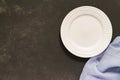 Top view of empty served plate, gray textile napkin on black concrete background. Copy space