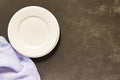 Top view of empty served plate, gray textile napkin on black concrete background. Copy space