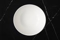 Top view of empty white plate on black marble table