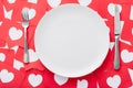 View of empty white plate, knife and fork on red paper cut cards with hearts symbols Royalty Free Stock Photo