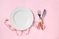 Empty white plate with a knife and fork wrapped in measuring tape on pink background Royalty Free Stock Photo