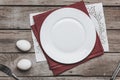 Top view of empty white plate on napkins and Easter eggs on wooden table Royalty Free Stock Photo