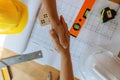 Top view of engineer, architect, construction worker team hands shaking after plan project contract on workplace desk in meeting r