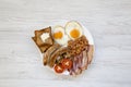 Top view English breakfast with fried eggs, sausages, beans, bacon and toasts over white wooden background. Flat lay. From