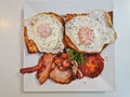 Top view of English breakfast with sunny fried eggs, bacon, tomatoes, ham on Turkish flat grilled bread on white dish