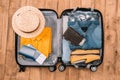 Top view of essentials for tourist with clothes, accessories and gadgets, wallet, passport, smartphone in bag. Royalty Free Stock Photo