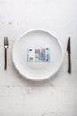 Top of view euro banknotes on white plate with fork and knife