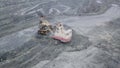 Top view of excavator in open pit. Excavator falls asleep rubble in dumper on outdoor quarry in extraction of minerals