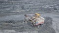 Top view of excavator in open pit. Excavator falls asleep rubble in dumper on outdoor quarry in extraction of minerals