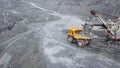 Top view of excavator in open pit. Excavator falls asleep rubble in dumper on outdoor quarry in extraction of minerals