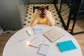 Top view of exhausted pupil boy tired from studying holding head head with hands sitting at desk with paper copybook Royalty Free Stock Photo