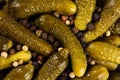 Top view, extreme close up of pickled gherkins small cucumbers sprinled with peppercorn mix. Macro food texture background