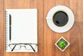 Eyeglasse and notepad with coffee cup on wood deck