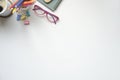 Top view eyeglasses, coffee cup and variety stationery on white table with copy space