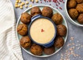 Top view of falafel laid out in a circle on a mint plate with sauce in the center. Pink pepper, pink himmalay salt, chickpea,